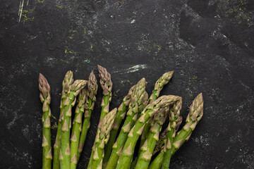 Bunch of fresh green asparagus on black surface copy space