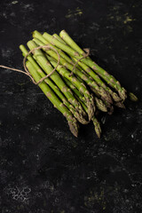 Bunch of fresh green asparagus on black surface vegetables