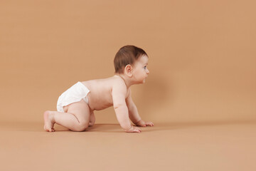 Cute little baby crawling on beige background
