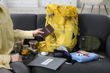 Survival kit. Woman packing different emergency supplies on sofa indoors, closeup