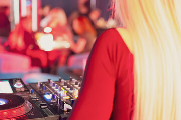A DJ performing at a nightclub, focused on mixing tracks with professional equipment. The vibrant...