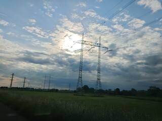 High-voltage power line towers in open countryside fields during daylight.