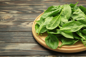 Fresh spinach leaves on cutting board on brown wooden background