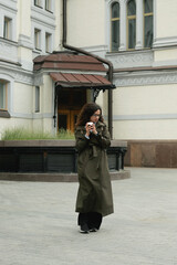 Stylish woman walking city streets with coffee