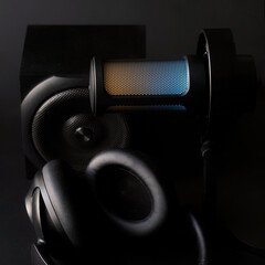 Close-up of a modern LED-lit microphone and headphones on a dark background, perfect for podcasting and live broadcasting materials. Photo, selective focus