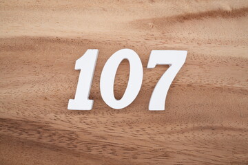 The numbers are made of white painted wood placed on a brown wooden floor.