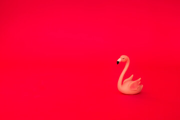 A pink flamingo figurine on a pink background. Cute statuette of an exotic sleeping bird on an isolated bright background.