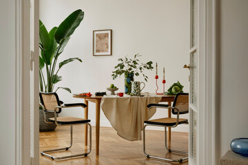 Dining table with lush greenery, playful red candleholders, and a mix of textures. A cozy and...