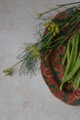 Green carob beans and fennel on textured background. Perfect for farming presentations, botanical visuals, or crop diversity promotions.