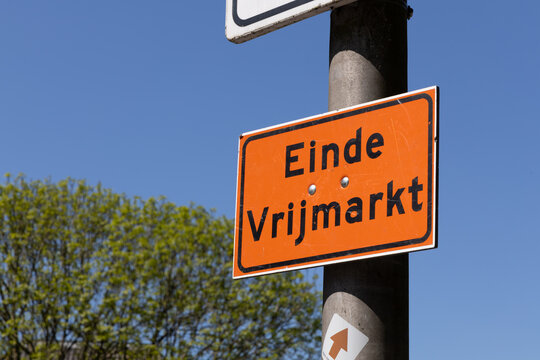 An orange sign in Utrecht, Netherlands, reads "Einde Vrijmarkt" (End of flea market), mounted on a pole against a clear blue sky. Utrecht, the Netherlands. 27 April 2025.