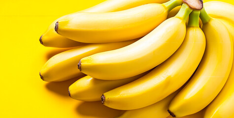 Neatly arranged yellow bananas. Fresh yellow bananas are clustered on a bright yellow background, highlighting their smooth texture.
