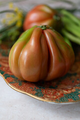 Colourful heirloom tomato and vegetables on the ornate plate. Can be used in vegetarian menus, food posters, or seasonal promotions.
