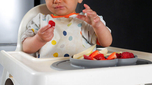 Baby taking fruit pieces from a grey silicone plate, baby led weaning