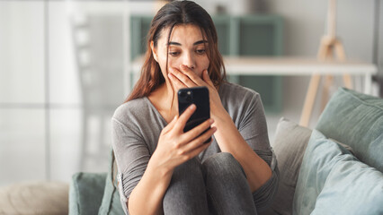 Woman reading some bad news on her smart phone, feeling sad and worried