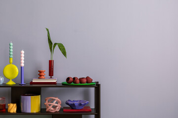 Colorful composition on blue wall with black shelf, design accessories, and decorations vases with leaf, candels and copy space. Home decor. Template...