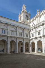Obraz premium Beautiful cloister courtyard of São Vicente de Fora historic monastery, featuring arches, blue azulejos tiles, and classical architecture under blue skies. Lisbon, Portugal. 26 February 2025
