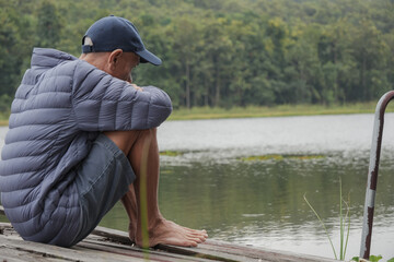 A sad asian senior man with lonely alone in a park, natural background, He thinking about something, Elderly health concept, depression and mental health, World Senior Citizen's Day.