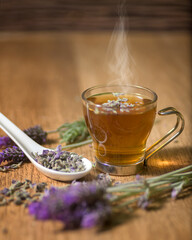 Cup of lavender tea on a wooden table surrounded by lavender flowers. Ideal for bedtime.