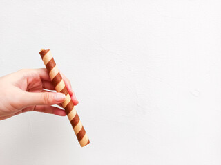 Crispy chocolate wafer roll held in hand against a clean white background—perfect for dessert brands, snack ads, or minimalist food packaging with a modern touch