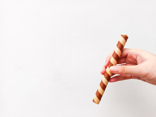 Crispy chocolate wafer roll held in hand against a clean white background—perfect for dessert brands, snack ads, or minimalist food packaging with a modern touch