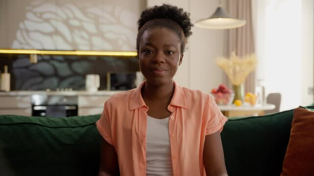 Happy smiling African American ethnic business woman female girl businesswoman spectator switch channel remote controller watching TV television program series film eating popcorn snack at home couch