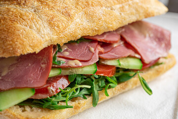 Closeup on portion of ciabatta sandwich with meat and salad