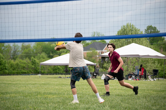 Doubles volleyball player approaching to hit the ball while his partner is setting him