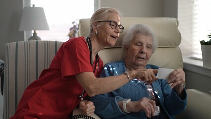 A caregiver engages with a senior resident at a memory care facility, focusing on a card during an...