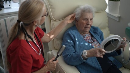 Obraz premium A caregiver interacts with an elderly woman in a home healthcare environment, fostering engagement and connection while sharing objects.