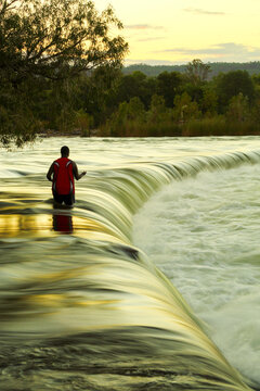 A solitary man uses a hand line fishing for barramundi at Ivanhoe Crossing on the Ord River.