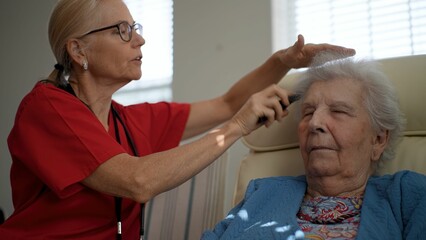 A caregiver gently assists an elderly woman in a healthcare facility, enhancing her engagement and comfort during a personal care moment in the afternoon.