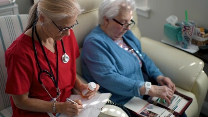 A caregiver in red scrubs engages warmly with an elderly woman in a light blue cardigan, promoting cognitive interaction in a healthcare setting.