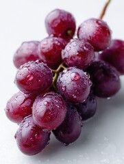 Fresh, vibrant grapes with water droplets, arranged on a clean white surface