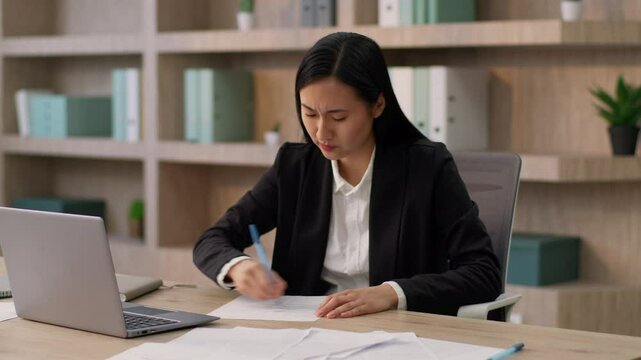 Stressed angry mad Asian Japanese office worker manager business woman Chinese Korean female businesswoman writing report document notes bad idea lack creativity crumple sheet paper throw away indoor