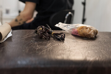 Tattoo artist creating a custom design for a young woman in a cozy Tbilisi studio. Details of the process, tattoo tools, ring light photography, and creative atmosphere