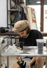 Tattoo artist creating a custom design for a young woman in a cozy Tbilisi studio. Details of the process, tattoo tools, ring light photography, and creative atmosphere