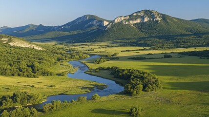 Fototapeta premium Aerial View of a Winding River Through Lush Green Valley and Mountains