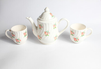 white ceramic teapot and cup with floral pattern isolated on white background
