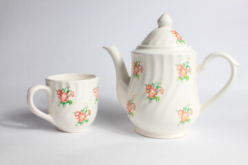 white ceramic teapot and cup with floral pattern isolated on white background