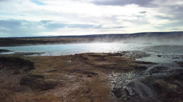 The most famous hot water geyser in Iceland, boiling and waiting to erupt. The Geysir can hurl boiling water up to 60 meters in the air. Camera panning to the right