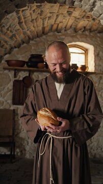 Moine joyeux tenant un pain dans une cuisine rustique en pierre

