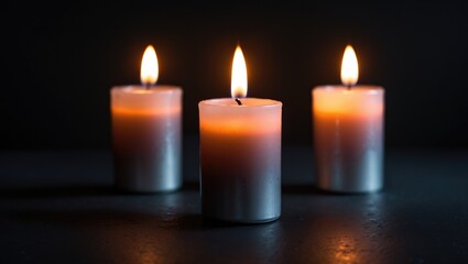 A trio of votive candles glowing in darkness, evoking a mood of romance or devotion
