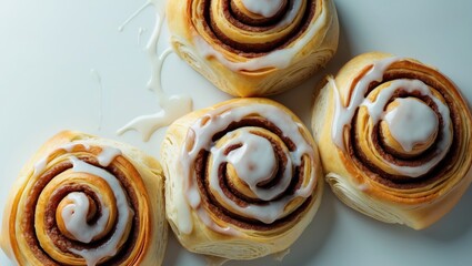 Fototapeta premium Cinnamon buns made from puff pastry with icing in the background, overhead view