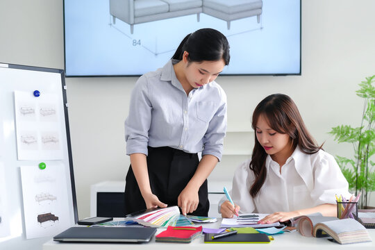 Asian Interior Designers Team at Work Selecting Fabric Swatches for Home Decorating and Furniture Design on Table with Color Palette in Studio