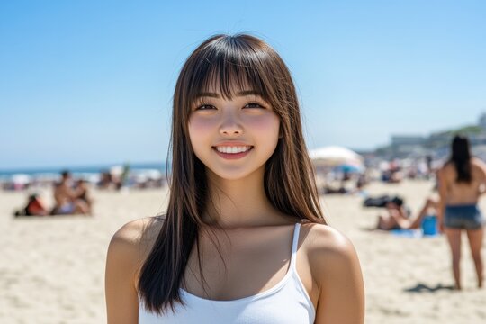Smiling young woman enjoying a sunny beach day in Japan amidst a lively atmosphere of beachgoers and clear skies