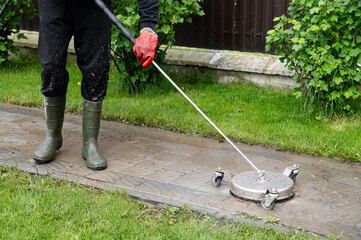 Professional paving stone cleaning. Cleaning a stamped concrete patio with a pressure washer in a residential garden during the day