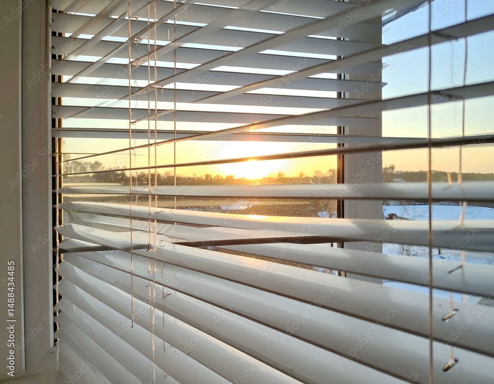 Poster sunset view through slightly open window blinds. warm golden hour light.
