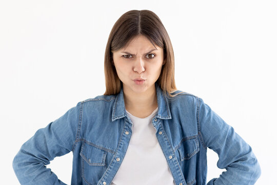 Hmm. Let me think. Studio shot of cute girl looking at camera with angry and confused expression, raising one brow as if having good idea, planning something