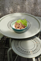 Bowl of Fried Chicken with Buttermilk Sauce Garnished With Lettuce on a Decorative Green Metal Table in a Garden Setting