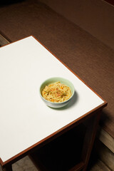 Bowl of Noodles Placed on a Simple Wooden Table in a Cozy Setting, Emphasizing Minimalism and Comfort